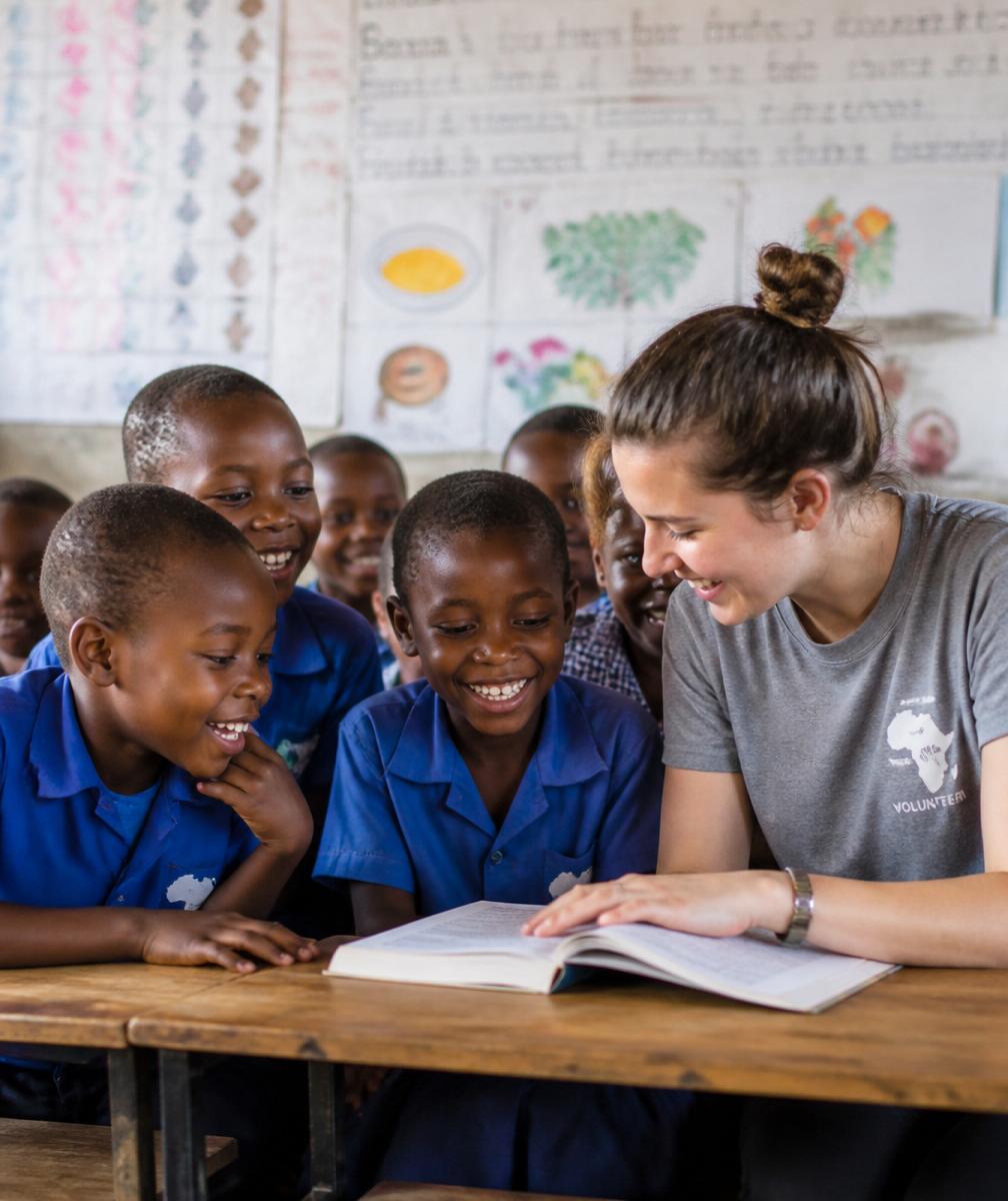 A volunteer reading with joyful schoolchildren in a rural classroom